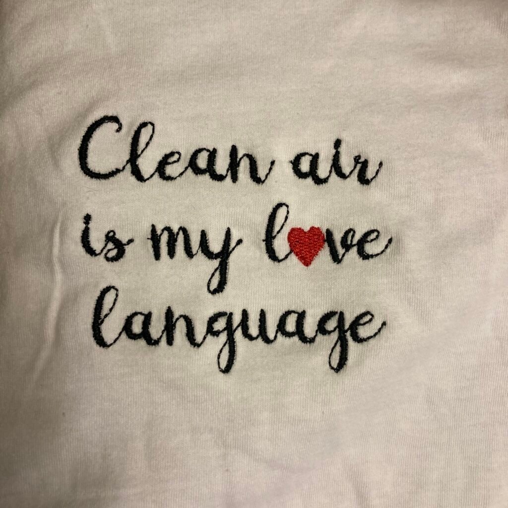 air_square Thin black script font on a white t-shirt saying "clean air is my love language" with a heart for the o in love